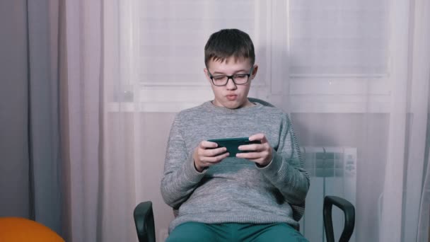 Удивленный ребенок в очках, смотрящий видео в мобильном приложении на смартфоне. — стоковое видео