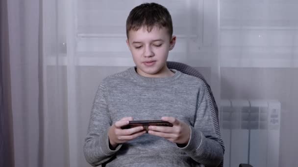 Przystojny chłopak mówi na smartfonie online w pokoju — Wideo stockowe