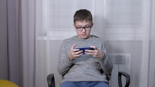 Smart Boy in Glasses Een video bekijken in een mobiele app op een smartphone. — Stockvideo