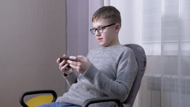 안경을 쓴 똑똑 한 아이는 스마트폰을 사용하여 친구들 과 이야기를 나눈다. 사이드 뷰. 4K. — 비디오