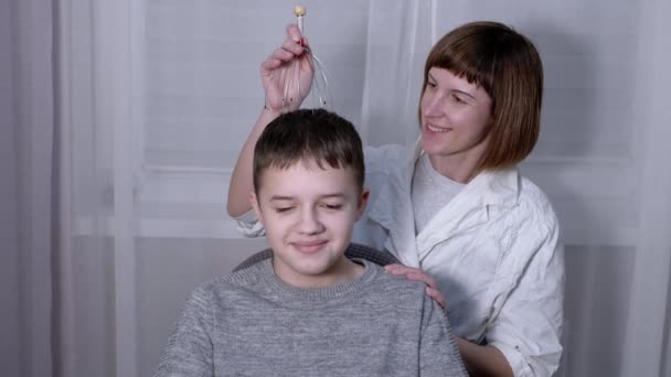 Masseuse Massage la tête d'un enfant avec un masseur d'acupuncture capillaire — Video