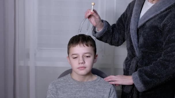 Женский массаж головы ребенка с помощью массажера иглоукалывания — стоковое видео