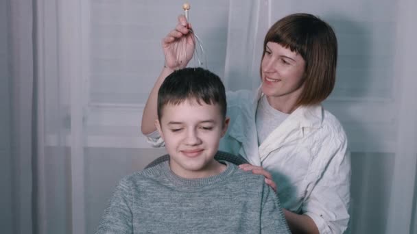 Masérka masíruje hlavu dítěte s kapilárním akupunkturním masérem — Stock video