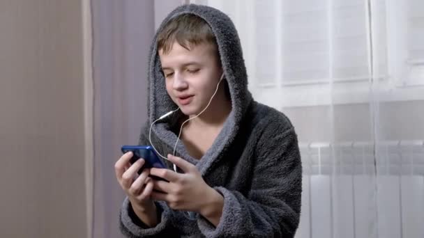 Despreocupado criança dança alegremente ouve música em fones de ouvido usando um smartphone — Vídeo de Stock