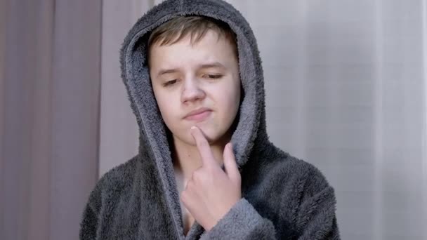 Sfrustrowany nastolatek dotyka, naciskając pryszcze na twarz z jego palec w pokoju — Wideo stockowe