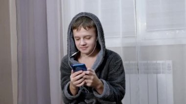 Dertsiz Çocuk Neşeli Dans eder Akıllı telefon kullanarak kulaklıkla müzik dinler