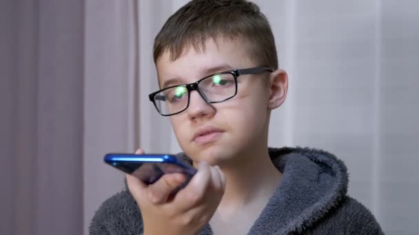 Niño triste en gafas sostiene un teléfono inteligente en las manos, Habla a través de Video Link en la habitación — Vídeos de Stock