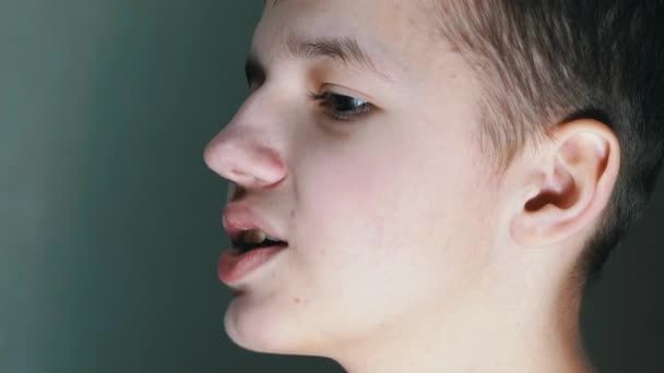 Nahaufnahme eines Gesichtsprofils eines sprechenden lächelnden Teenagers, der nach unten schaut. Seitenansicht — Stockvideo