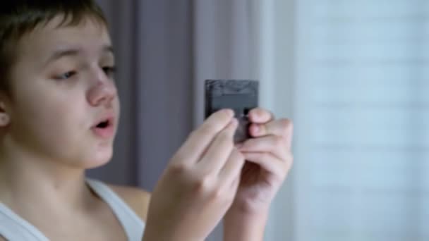 Surprised Child Examines an Old Vintage Audio Cassette in his Hands. Fechar — Vídeo de Stock