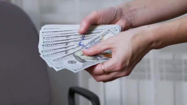 Női kezek számolnak 100 dollárért, szétszórva egy rajongóban, közel a fotelhez. — Stock videók