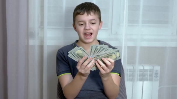 Happy Child egy csomó 100 dolláros számlát tart a kezében, mellkason szorongatva őket. — Stock videók