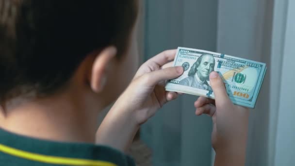 成功的青少年在房间里数着一堆100美元的钞票。后视镜变焦 — 图库视频影像