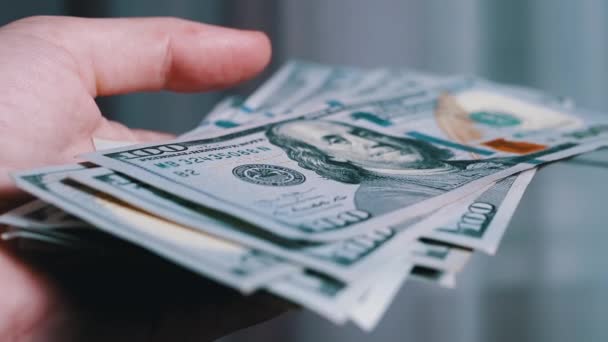 Close-up of Male Hands Holding a Pack of 100 Dollar Bills on Blurred Background — Video