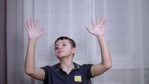 Surprised Child Raising Arms, Palms Up and Looking Up, Sits in Chair in the Room — Stock Video