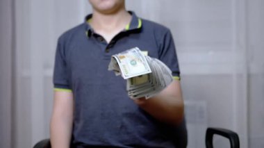 Zengin çocuk elinde 100 dolarlık banknotlar tutuyor ve sallıyor.