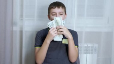 Mutlu Çocuk 'un elinde bir sürü 100 Dolarlık banknot var ve onları göğsüne yapıştırıyor.