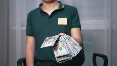 Zengin çocuk elinde 100 dolarlık banknotlar tutuyor ve sallıyor.