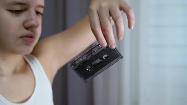 Dítě drží starou černou kazetu ve svých rukou a prohlíží si ji. 4K — Stock video