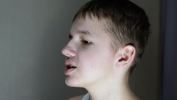 Zbliżenie profilu twarzy mówiącego uśmiechniętego nastolatka patrzącego w dół. Widok z boku — Wideo stockowe