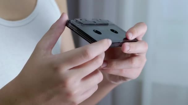 Child Holds an Old Black Vintage Audio Cassette in Hands and Rewinds the Tape — Stock Video