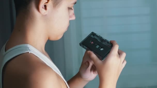 Child Holds an Old Black Vintage Audio Cassette in Hands and Rewinds the Tape — стоковое видео