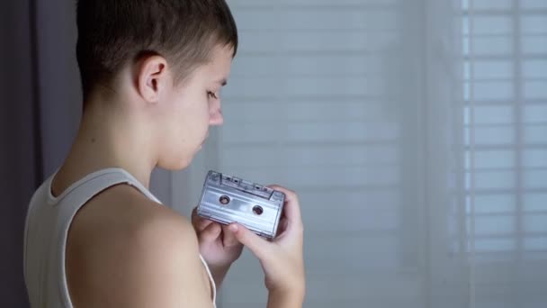 Kind hält eine alte schwarze Vintage-Audiokassette in den Händen und wickelt das Band zurück — Stockvideo