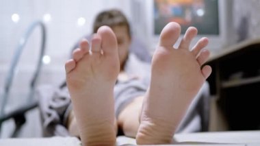 Yorgun Çocuk Parmaklarını oynatıyor, Parıldayan Çelenklerin Arkasında Yatakta Uzanıyor