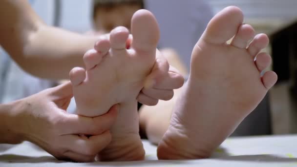 Mãos de massagista Massageie as pernas de uma criança em uma sala de massagem. Fecha. Zoom — Vídeo de Stock