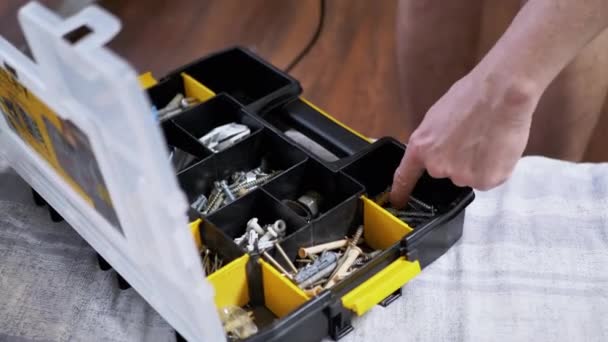 Male Hand Chooses Fasteners and Self-Tapping Screws from a Plastic Organizer. 4K — Vídeo de stock