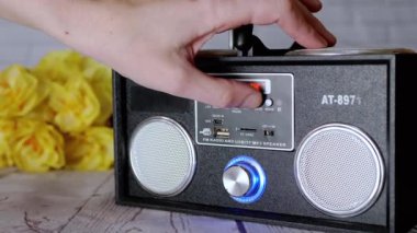 Kadın Elleri Basma Tuşları, Taşınabilir Ses Kayıt Cihazında Döndürme Kolu. Ses, oyun, mod. Oyuncu, masadaki çiçeklerin arka planına USB girdisi olan iki stereo hoparlörlü radyo.