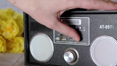 Kadın Elleri Basma Tuşları, Taşınabilir Ses Kayıt Cihazında Döndürme Kolu. Ses, oyun, mod. Oyuncu, masadaki çiçeklerin arka planına USB girdisi olan iki stereo hoparlörlü radyo.
