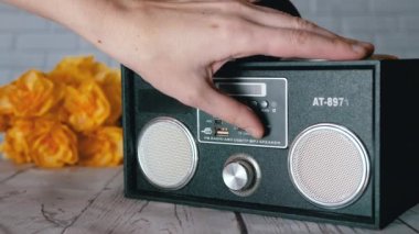 Kadın Elleri Basma Tuşları, Taşınabilir Ses Kayıt Cihazında Döndürme Kolu. Ses, oyun, mod. Oyuncu, masadaki çiçeklerin arka planına USB girdisi olan iki stereo hoparlörlü radyo.