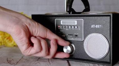 Kadın Elleri Basma Tuşları, Taşınabilir Ses Kayıt Cihazında Döndürme Kolu. Ses, oyun, mod. Oyuncu, masadaki çiçeklerin arka planına USB girdisi olan iki stereo hoparlörlü radyo.
