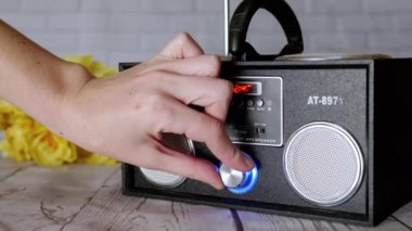 Kadın Elleri Basma Tuşları, Taşınabilir Ses Kayıt Cihazında Döndürme Kolu. Ses, oyun, mod. Oyuncu, masadaki çiçeklerin arka planına USB girdisi olan iki stereo hoparlörlü radyo.
