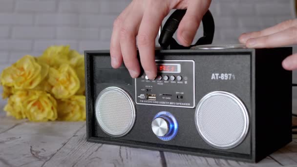 女性の手ポータブル現代的なオーディオテープレコーダーのボタンを押す 前のモード プレーヤー 机の上の花の背景にUsb入力を持つ2つのステレオスピーカーとラジオ — ストック動画