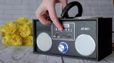 Kadın Elleri Basma Tuşları, Taşınabilir Ses Kayıt Cihazında Döndürme Kolu. Ses, oyun, mod. Oyuncu, masadaki çiçeklerin arka planına USB girdisi olan iki stereo hoparlörlü radyo.