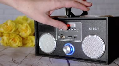 Kadın Elleri Basma Tuşları, Taşınabilir Ses Kayıt Cihazında Döndürme Kolu. Ses, oyun, mod. Oyuncu, masadaki çiçeklerin arka planına USB girdisi olan iki stereo hoparlörlü radyo.