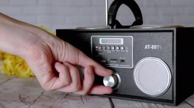 Kadın Elleri Basma Tuşları, Taşınabilir Ses Kayıt Cihazında Döndürme Kolu. Ses, oyun, mod. Oyuncu, masadaki çiçeklerin arka planına USB girdisi olan iki stereo hoparlörlü radyo.