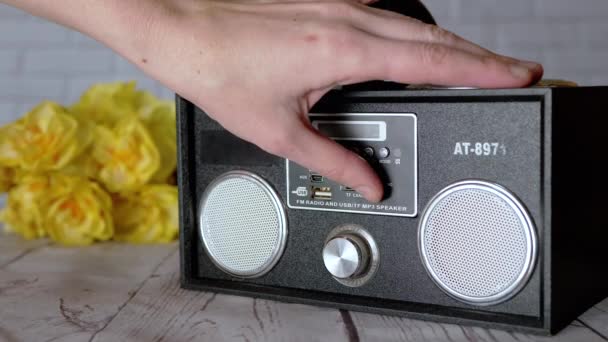 女性手压钮扣 用便携式录音带录音机旋转手柄 播放器 带两个立体声扬声器的收音机 带有Usb接口 背景为桌上的花朵 — 图库视频影像