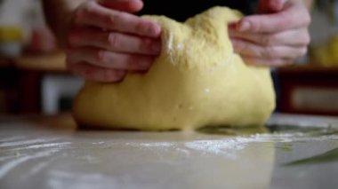Mutfak masasına un serpiştirilmiş kadın elleri hamur yoğurdu. Gevşek, sarı, ekmek ve çörek yapmak için yumuşak hamur. Ailemiz için lezzetli hamur işleri pişiriyorum. Yavaş çekim. Yakın plan..