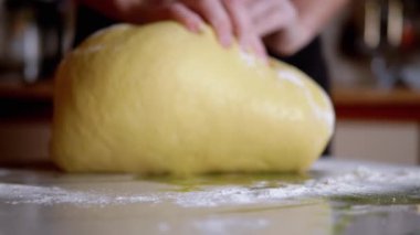 Mutfak masasına un serpiştirilmiş kadın elleri hamur yoğurdu. Gevşek, sarı, ekmek ve çörek yapmak için yumuşak hamur. Ailemiz için lezzetli hamur işleri pişiriyorum. Yavaş çekim. Yakın plan..