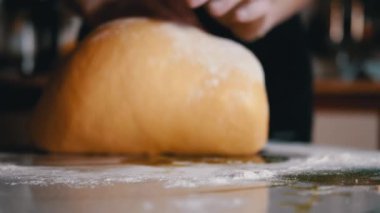 Mutfak masasına un serpiştirilmiş kadın elleri hamur yoğurdu. Gevşek, sarı, ekmek ve çörek yapmak için yumuşak hamur. Ailemiz için lezzetli hamur işleri pişiriyorum. Yavaş çekim. Yakın plan..