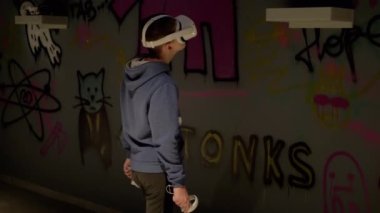 3d Gözlüklü Genç Oyun Kontrolörleri Sanal Gerçeklik Odasında Oynuyor. Mutlu çocuk karanlık odanın yanından geçiyor, VR test cihazını beyaz kulaklıkla hareket ettiriyor ve oynuyor. Uygulama. Cihaz. Yapay zeka.