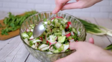 Sebze salatası, salatalık, salatalık, yeşillik ve sebzeyle karıştırılan eller. Yakın plan. Renkli yeşil soğan, maydanoz, turp ve salatalık sebzesi karışımı, yağ. Vejetaryen diyeti. Sağlıklı yemek..