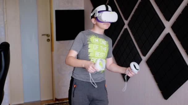 与游戏控制器一起玩3D眼镜的青少年在一个隔音室内玩耍 戴白色头盔的男孩带着耳机Vr测试仪走在房间里 虚拟现实 人工智能 — 图库视频影像