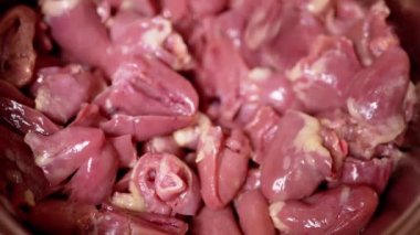 Bir sürü Taze, Soyulmuş, İçi boşaltılmış Çiğ Tavuk Kalpleri Tabağa Düşen Offal. Parlak kırmızı tavuk kalbi, ikiye bölünmüş. Beslenme eti. İkinci sınıfın yan ürünleri. Yoksulun yiyeceği. Satılık..