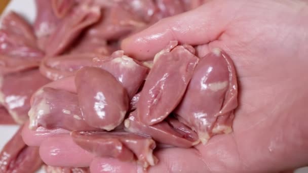 女性の手は プレート上に新鮮な生の皮チキンハートを置きます 接近中だ 多くの溝の光沢のある赤鶏の心 2つの半分にカットします 肉料理 2年生の副産物 貧しい人々のための安価な食品 — ストック動画