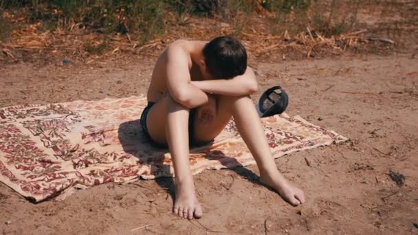 Sıkıcı Çocuk Kumda Kaputta Oturuyor Sıcak Güneş Sahilde Güneşleniyor Kafası — Stok video