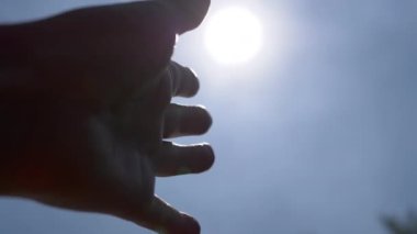 Siluet kadın eli gökyüzüne, güneşe, doğaya uzanan parlak güneş ışığına uzanıyor. Parmaklar güneşe dokunur parlamaya. Umut, hayal. Güneş ışınları. Hope, rica ediyorum. Özgürlük için. Gücünü geri kazan. Yaz zamanı..