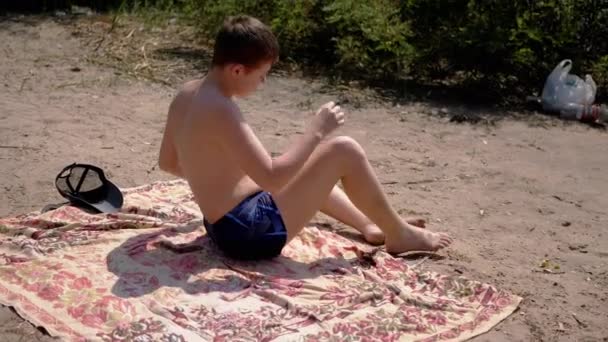 Niño Aburrido Sentado Una Terraza Arena Tomando Sol Playa Bajo — Vídeos de Stock